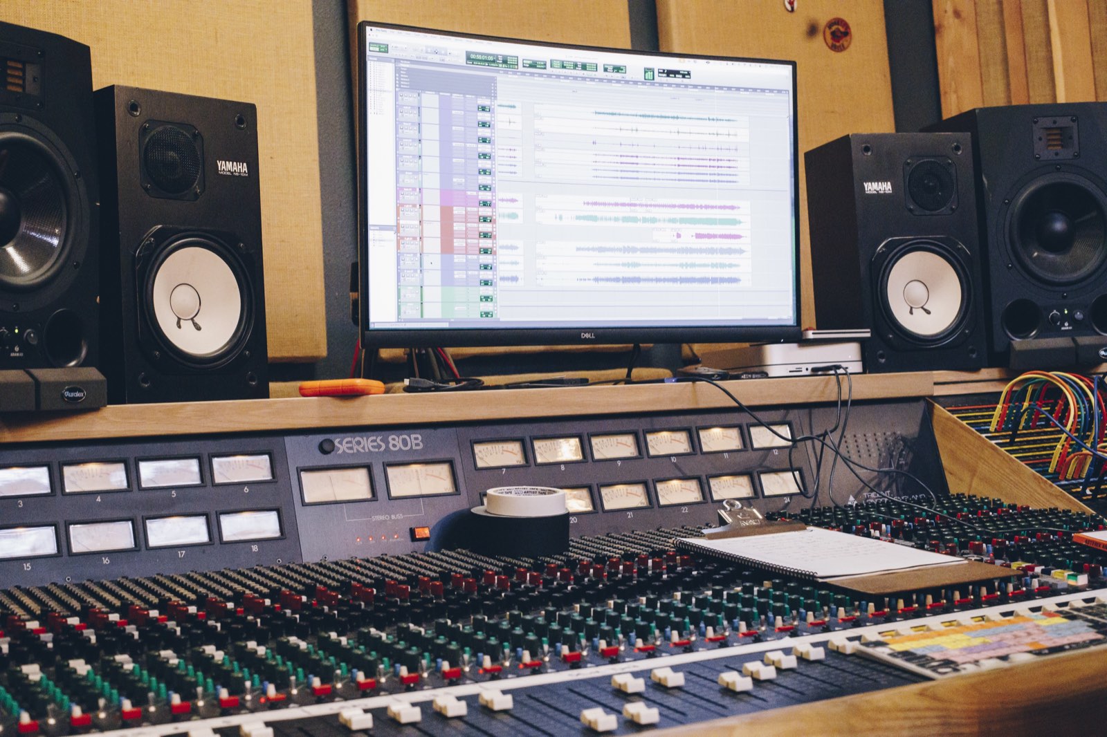A recording studio control room with an analog mixing console and studio monitors