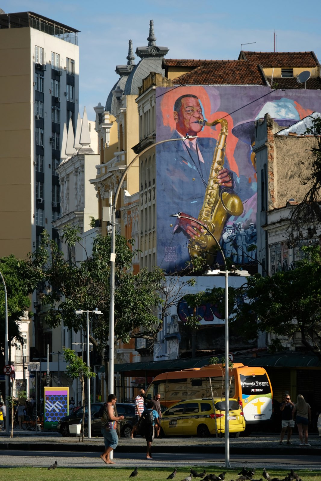 Mural of a saxophonist on a building above a city street